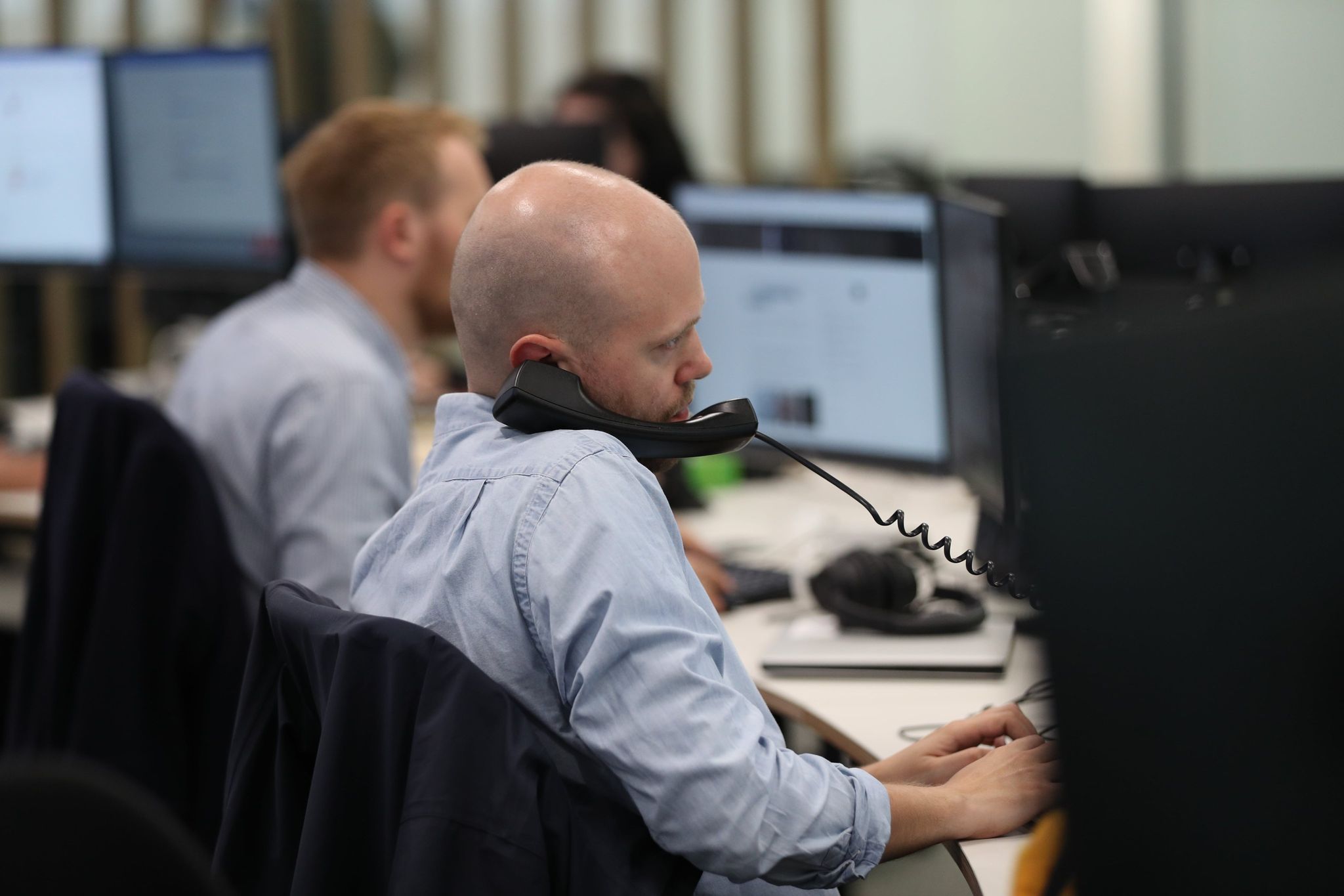 journalist on the phone in a busy newsroom